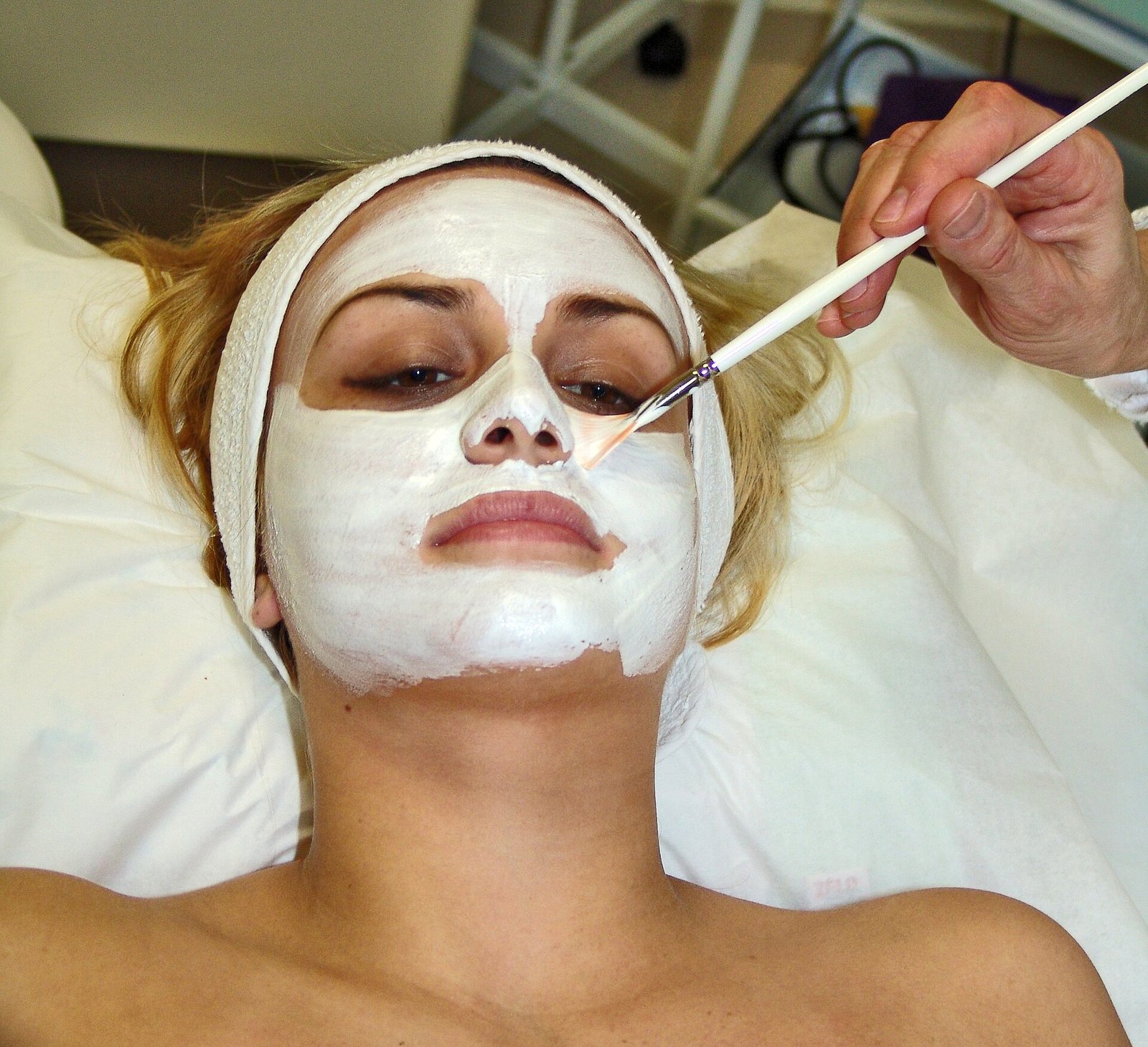 A woman wearing a creamy facial mask during a skincare treatment