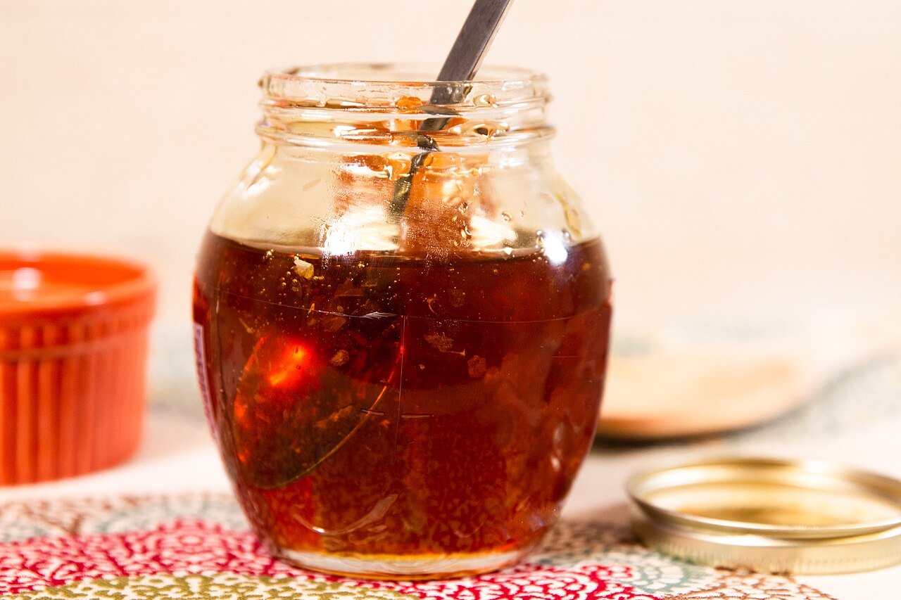 A small jar of raw honey with honeycomb