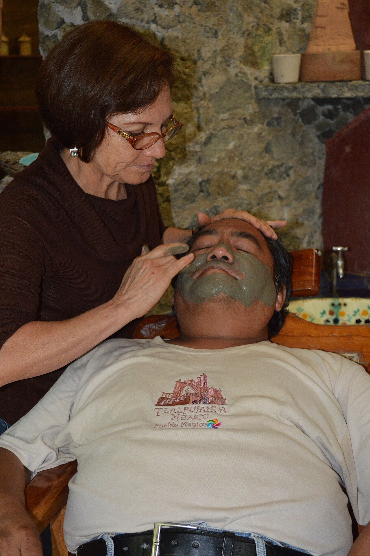 A thick mud facial mask being worn during a spa treatment